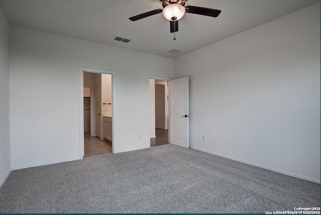unfurnished bedroom featuring carpet floors, visible vents, baseboards, a ceiling fan, and ensuite bath