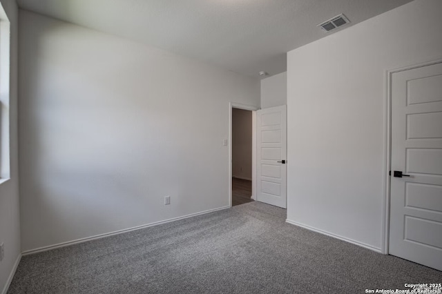 unfurnished bedroom featuring baseboards, carpet, and visible vents