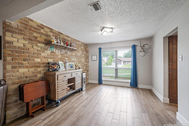 interior space with visible vents, a textured ceiling, baseboards, and wood finished floors