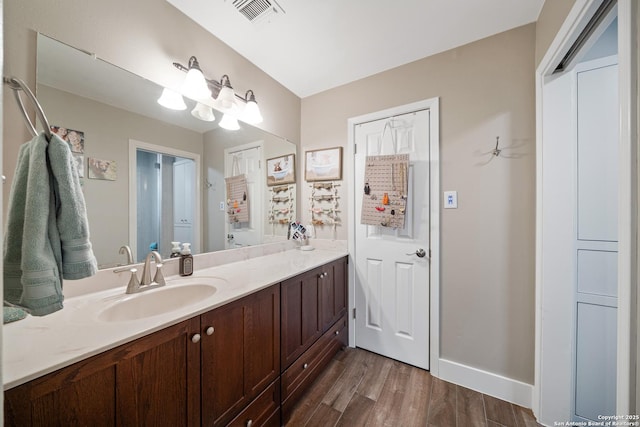 bathroom with vanity, baseboards, wood finished floors, and visible vents