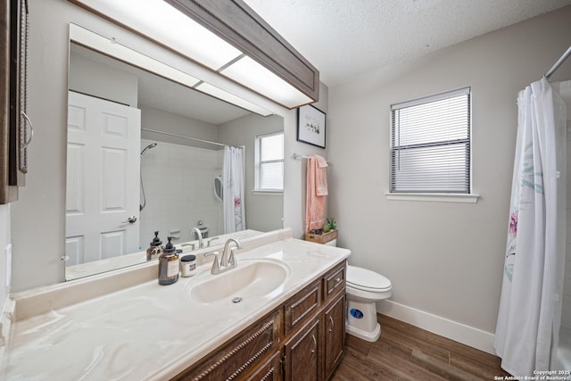 bathroom with vanity, curtained shower, wood finished floors, toilet, and baseboards