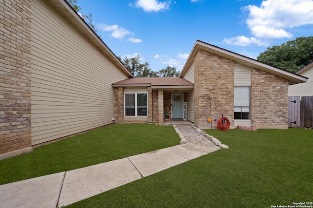 exterior space featuring fence, a front yard, and brick siding
