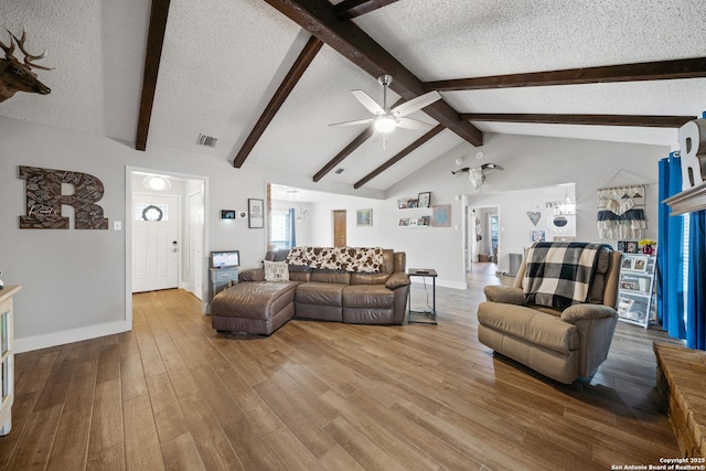 living area featuring baseboards, a textured ceiling, visible vents, and ceiling fan