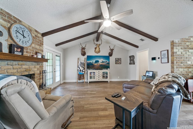 living area with a fireplace, light wood-style floors, ceiling fan, a textured ceiling, and lofted ceiling with beams