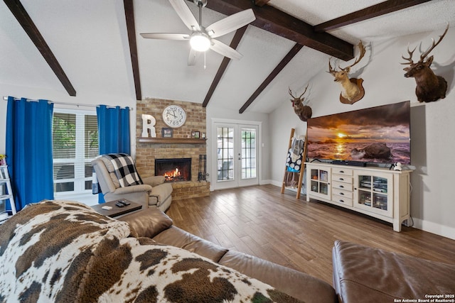 living area featuring baseboards, a ceiling fan, a brick fireplace, and wood finished floors