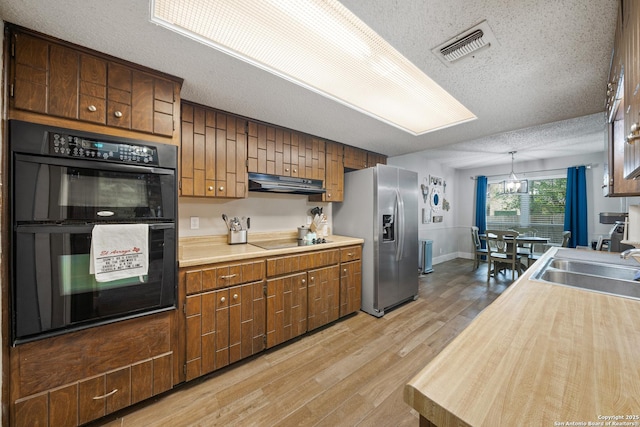 kitchen with visible vents, light countertops, a textured ceiling, and black appliances