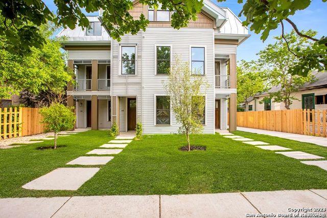 view of front of home featuring fence, a front lawn, and a balcony