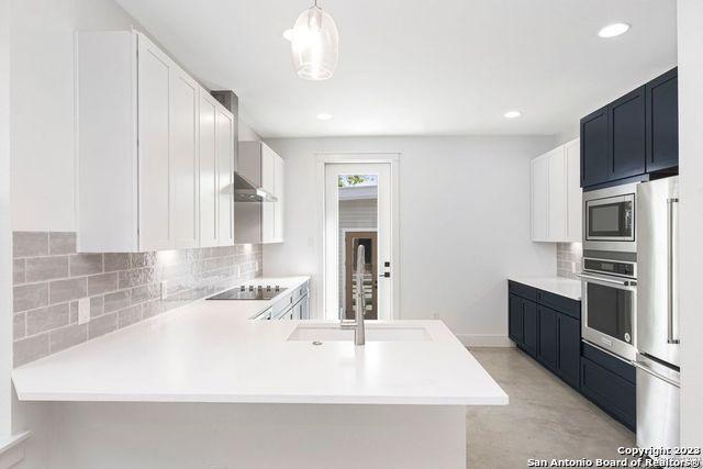 kitchen with tasteful backsplash, a sink, light countertops, a peninsula, and stainless steel appliances