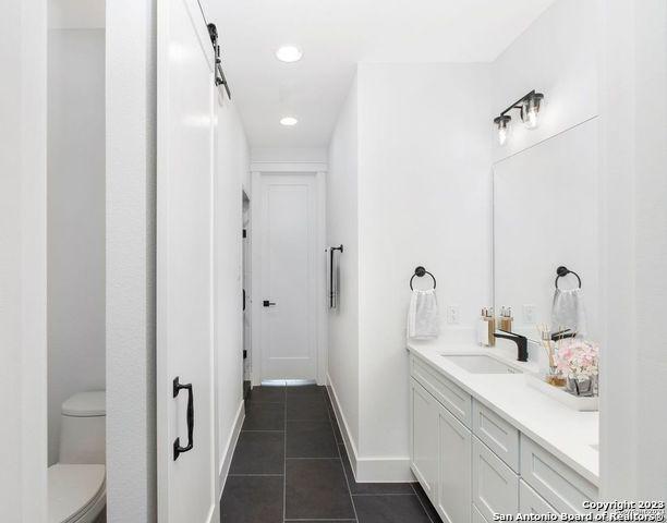 bathroom with tile patterned floors, baseboards, vanity, toilet, and recessed lighting