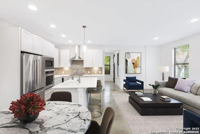 living room with baseboards, concrete flooring, and recessed lighting