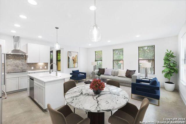 interior space featuring light countertops, concrete floors, wall chimney exhaust hood, recessed lighting, and backsplash