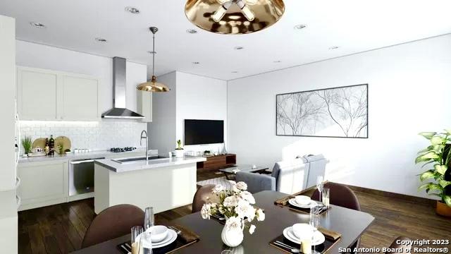 kitchen featuring wall chimney range hood, light countertops, tasteful backsplash, and dark wood-style flooring