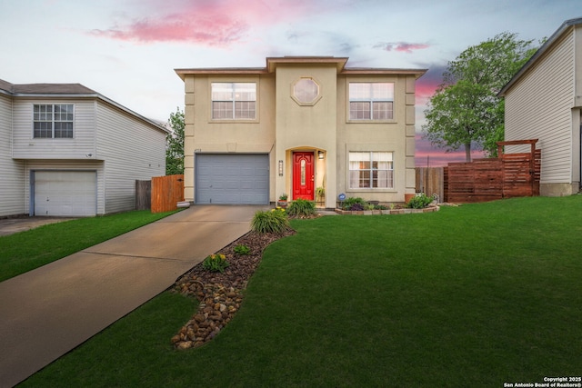 view of front facade featuring a lawn, stucco siding, fence, and driveway