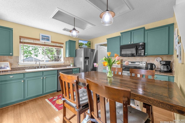 kitchen with a sink, a textured ceiling, decorative backsplash, and stainless steel appliances