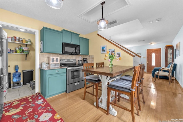 kitchen featuring electric range, black microwave, light wood-style floors, backsplash, and visible vents