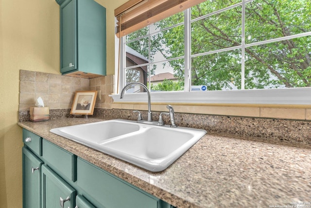 kitchen featuring a sink, decorative backsplash, green cabinetry, and light countertops