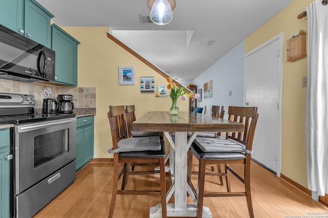 dining space featuring light wood-type flooring, baseboards, and visible vents