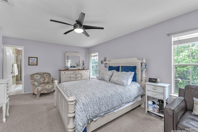 bedroom with visible vents, ensuite bathroom, ceiling fan, light colored carpet, and a textured ceiling