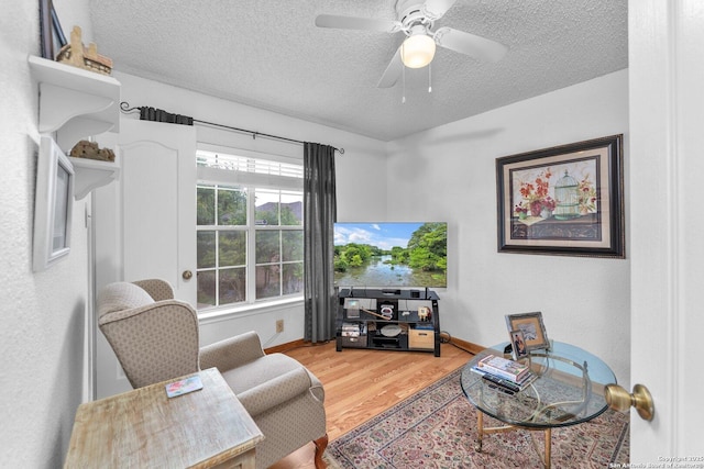 sitting room with baseboards, a textured ceiling, ceiling fan, and wood finished floors