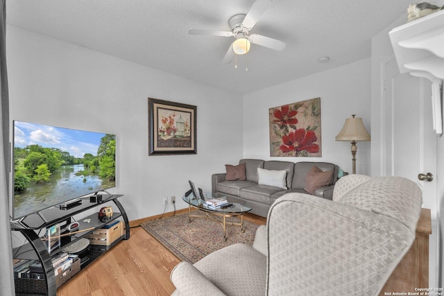living area featuring baseboards, a ceiling fan, and wood finished floors