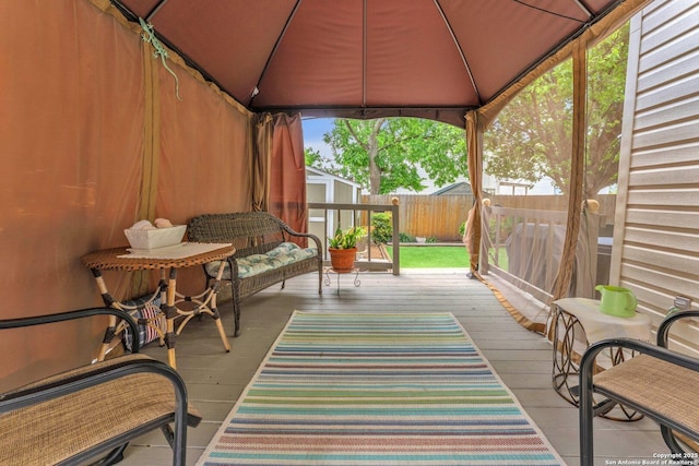 wooden deck with a gazebo, a fenced backyard, a shed, and an outbuilding