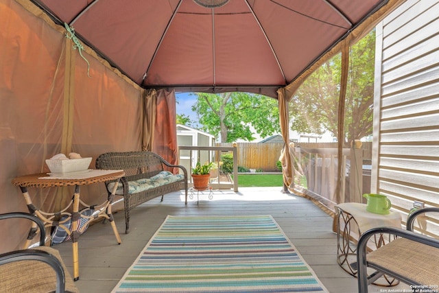wooden terrace featuring fence, a storage unit, an outdoor structure, and a gazebo