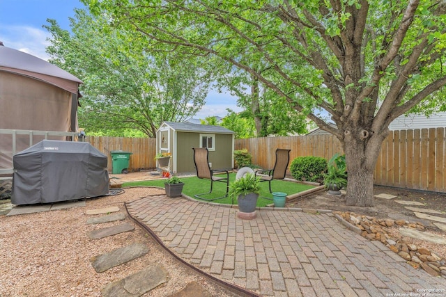 view of patio with an outbuilding, a fenced backyard, a storage shed, and area for grilling
