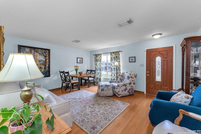 living area featuring a textured ceiling, visible vents, and light wood-style floors