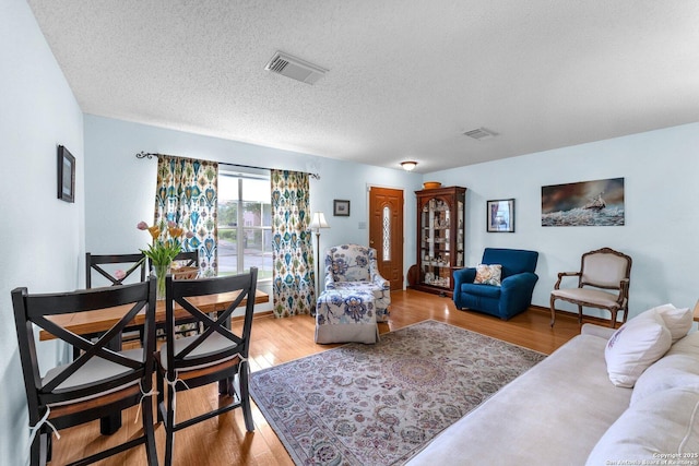 living area with light wood-type flooring, a textured ceiling, and visible vents