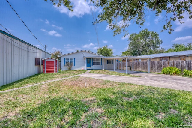 back of property featuring fence, a storage shed, an outbuilding, concrete driveway, and a yard