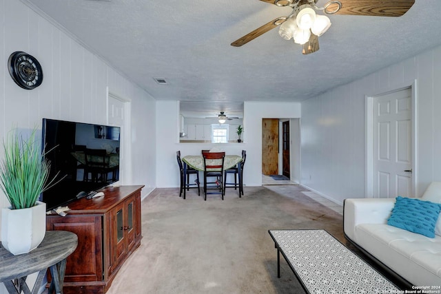 living area with visible vents, a textured ceiling, ceiling fan, and baseboards
