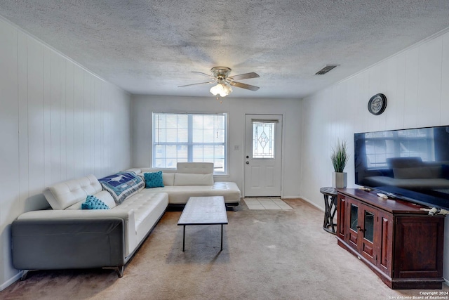 carpeted living room featuring wooden walls, a ceiling fan, a textured ceiling, and visible vents
