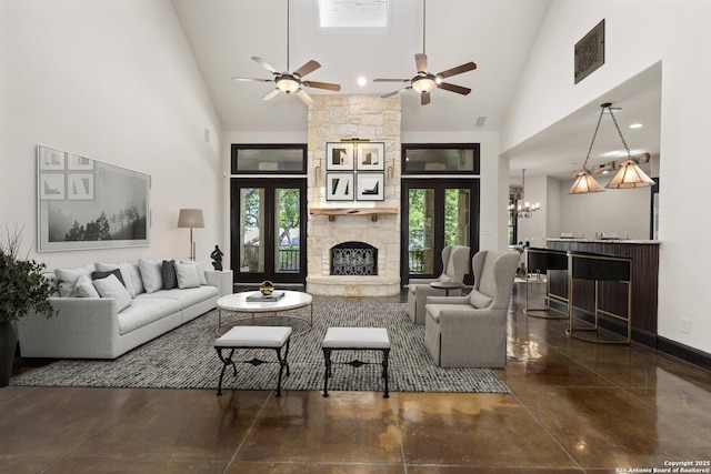 living area with visible vents, finished concrete flooring, a fireplace, high vaulted ceiling, and ceiling fan with notable chandelier
