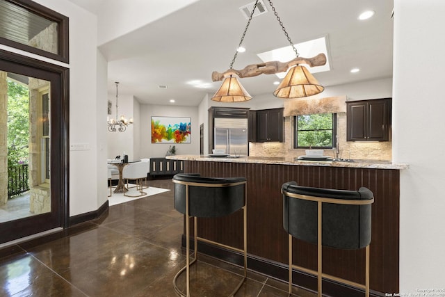 kitchen featuring a healthy amount of sunlight, decorative backsplash, a breakfast bar area, visible vents, and stainless steel built in fridge