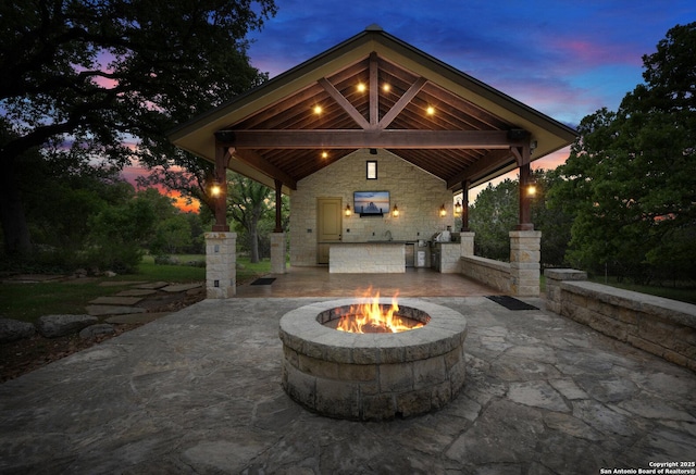 view of patio / terrace with exterior kitchen, a gazebo, and an outdoor fire pit