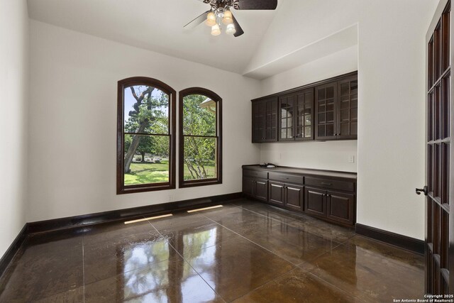 empty room featuring a ceiling fan, baseboards, and vaulted ceiling