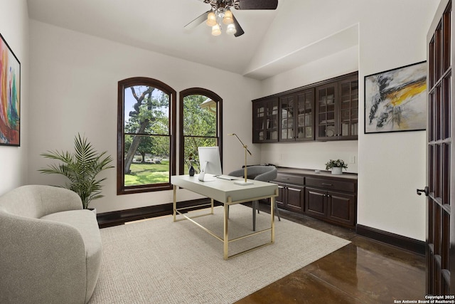 office area with finished concrete floors, a ceiling fan, baseboards, and vaulted ceiling