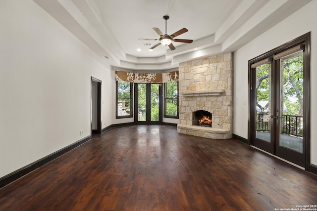 unfurnished living room featuring french doors, ceiling fan, a wealth of natural light, and a raised ceiling