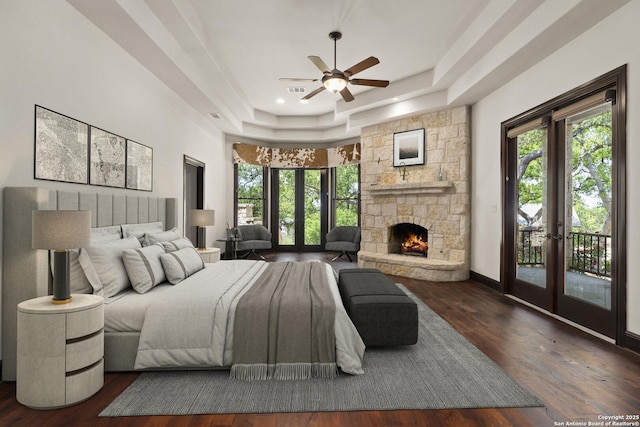bedroom featuring a tray ceiling, access to outside, multiple windows, and wood finished floors
