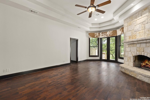 unfurnished living room featuring a ceiling fan, visible vents, dark wood-style floors, and a fireplace