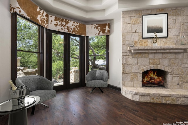 living area featuring baseboards, plenty of natural light, a fireplace, and hardwood / wood-style floors