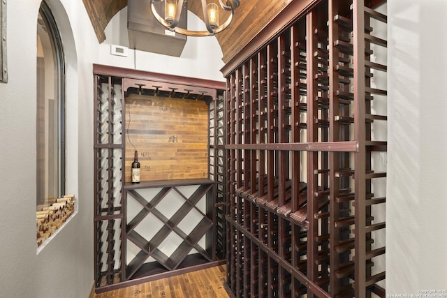 wine area featuring arched walkways, wood finished floors, and a chandelier
