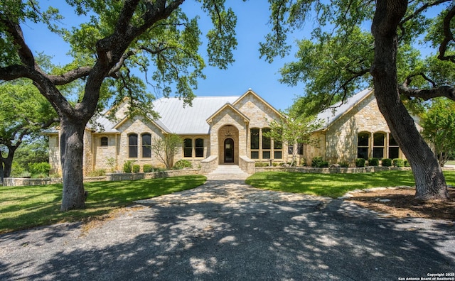view of front of house featuring a front yard, metal roof, and stone siding