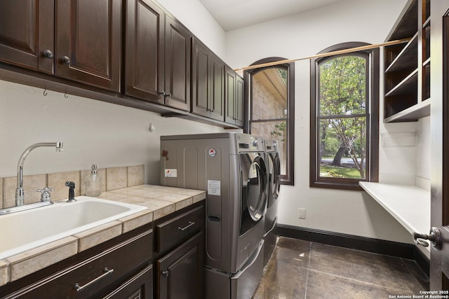 laundry room with a sink, baseboards, independent washer and dryer, and cabinet space