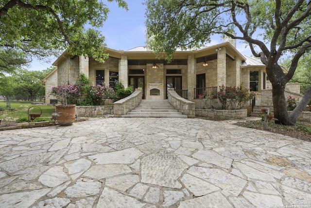 view of front of house featuring covered porch, stone siding, and metal roof