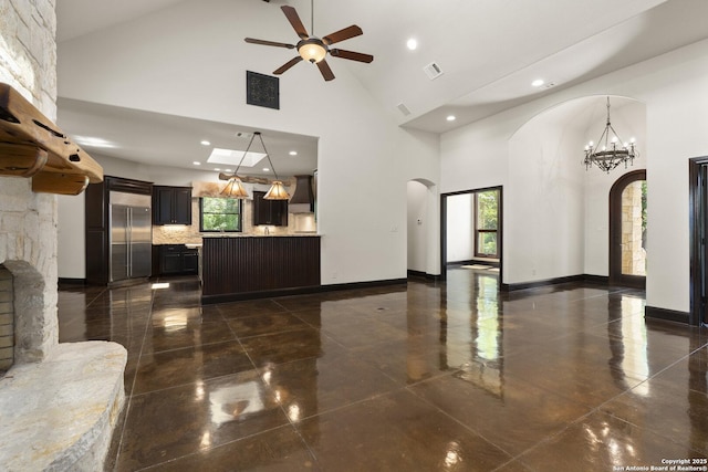 unfurnished living room with arched walkways, high vaulted ceiling, visible vents, and a wealth of natural light