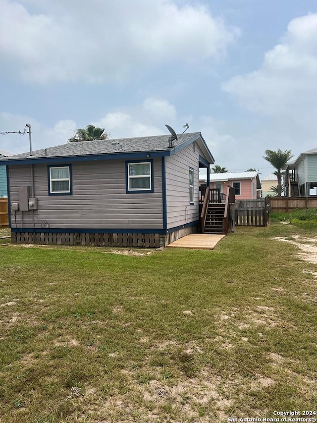 view of home's exterior with a yard, a deck, stairway, and fence