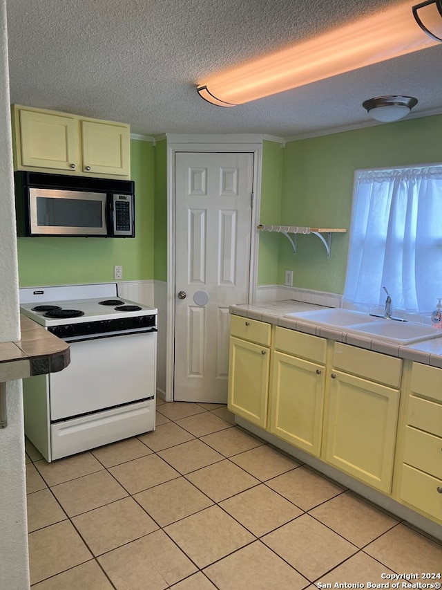 kitchen with a sink, a textured ceiling, stainless steel microwave, light tile patterned floors, and white electric stove
