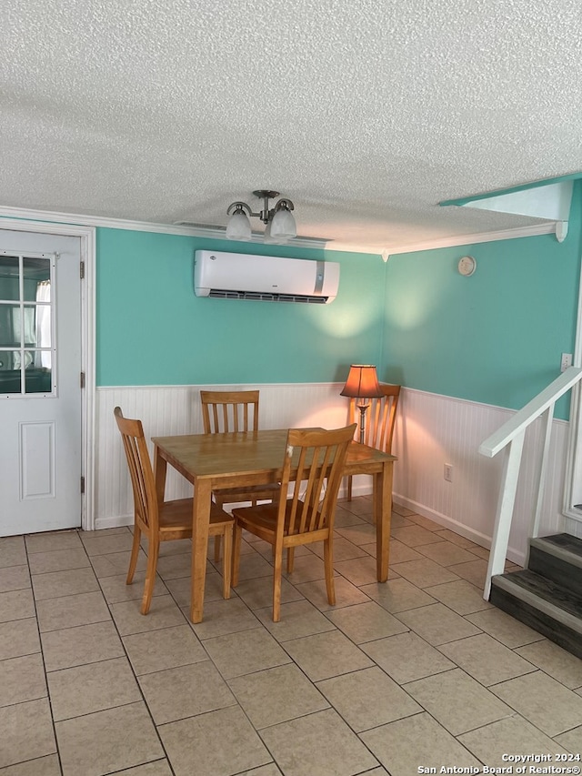 dining space with an AC wall unit, a textured ceiling, light tile patterned floors, and wainscoting