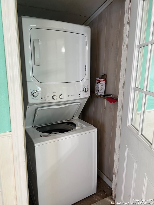 clothes washing area with laundry area, wood walls, and stacked washer / dryer